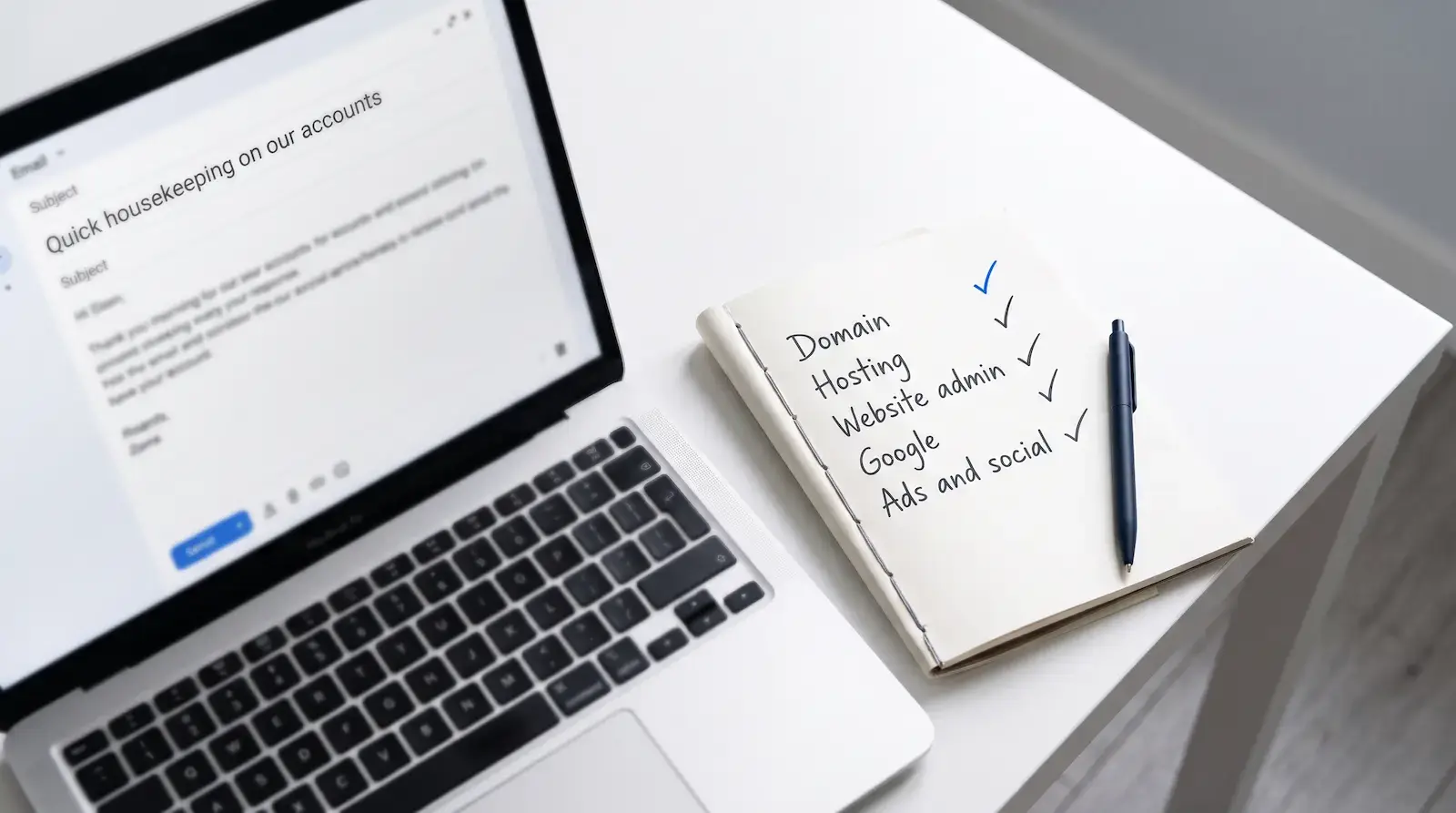 Laptop showing an email titled Quick housekeeping on our accounts, next to a notebook checklist of domain, hosting, website admin, Google, and ads and social